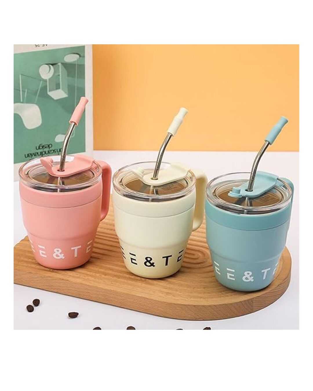 Tres tazas térmicas de acero inoxidable en colores rosa, crema y azul claro, con tapas antideslizantes y pajitas flexibles, sobre una base de madera.