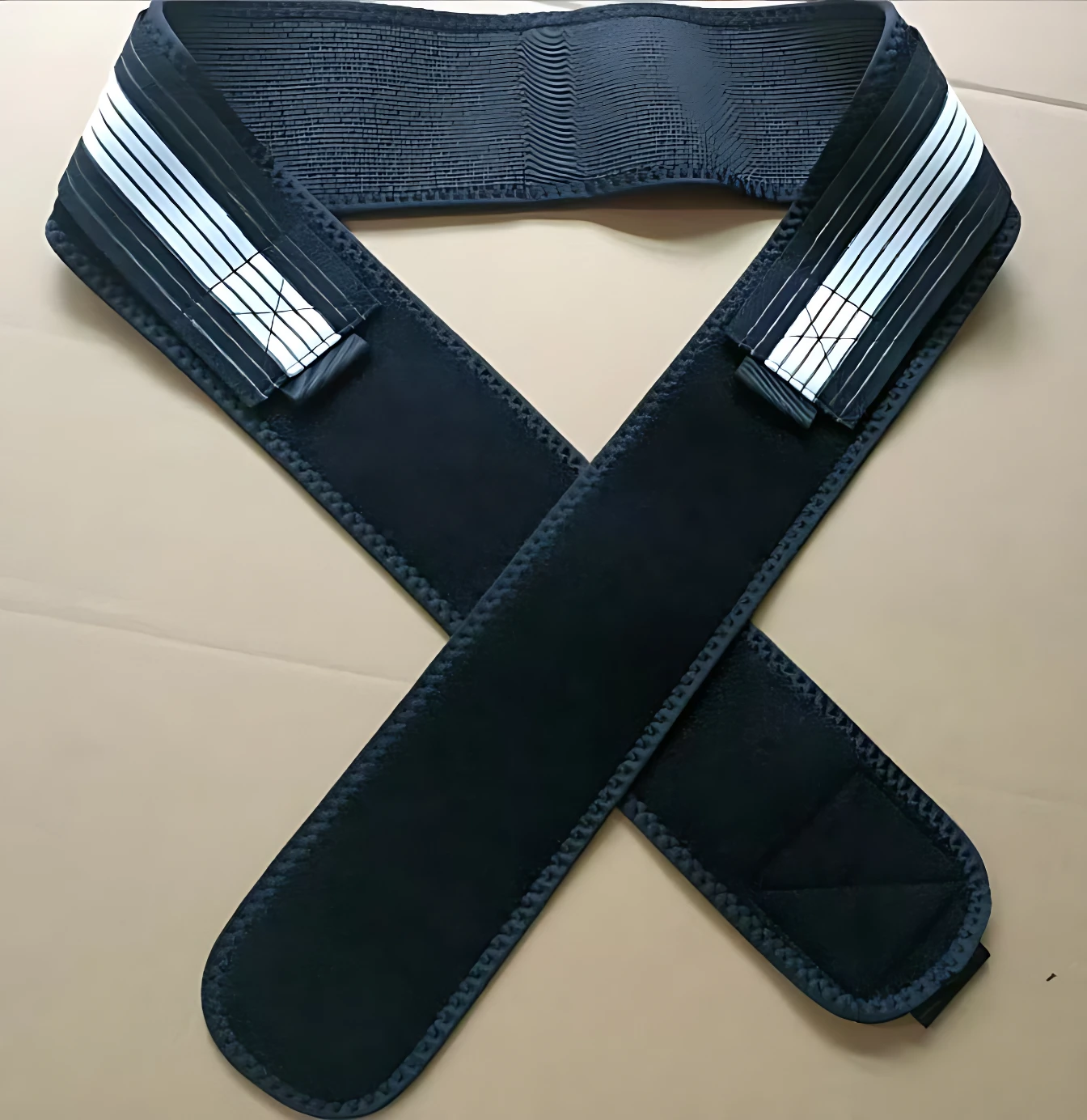 Cinturón lumbar negro con correas cruzadas y cierres de velcro, diseñado para soporte y ajuste en la zona baja de la espalda.